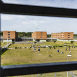 Blick aus einer Gefaengniszelle zum GORILLA Workshop der im Freien stattfindet.