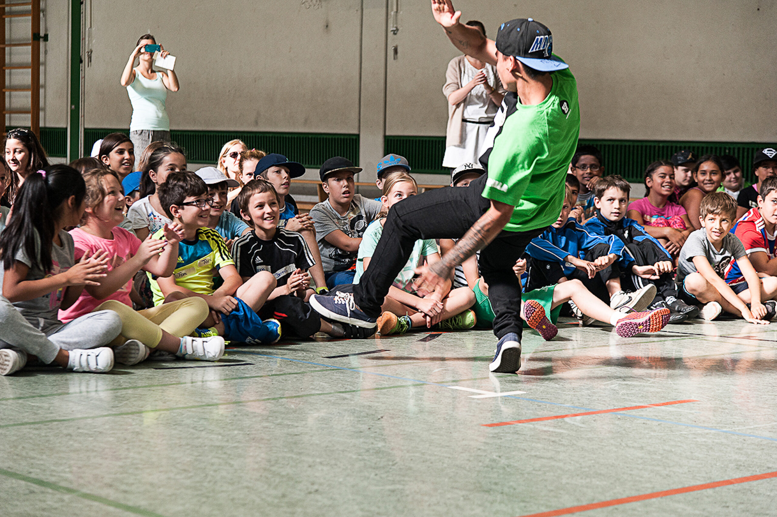 GORILLA Botschafter Ninja macht einen Breakdancetrick vor einer Gruppe von Kids im Rahmen eines GORILLA Workshops.